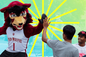The IU East mascot giving a young man a high five while his friends look on