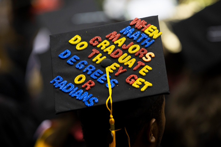 Closeup of a grad cap with alphabet letters reading, when math majors graduate do they get degrees or radians