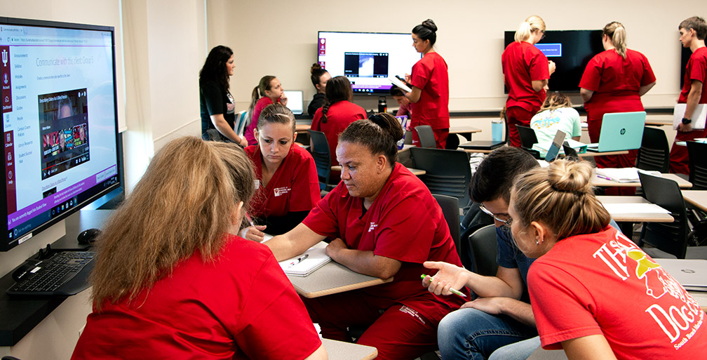 Nursing students working collaboratively at tech stations.