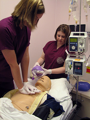 Two students practicing life-saving procedures on simulation dummy.