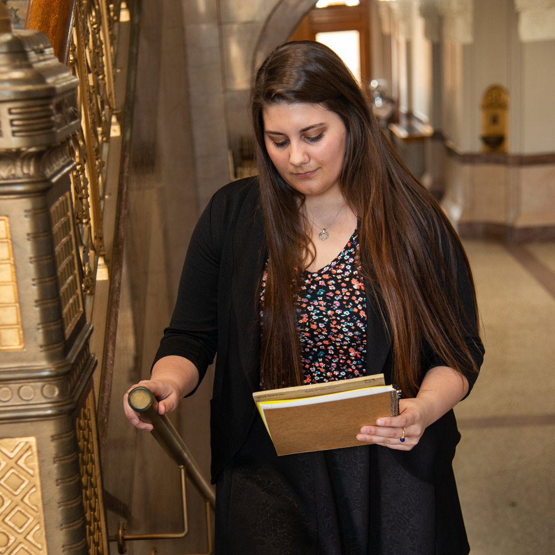 Caysey Farmer examining some documents while walking up stairs in the Rush County courthouse.