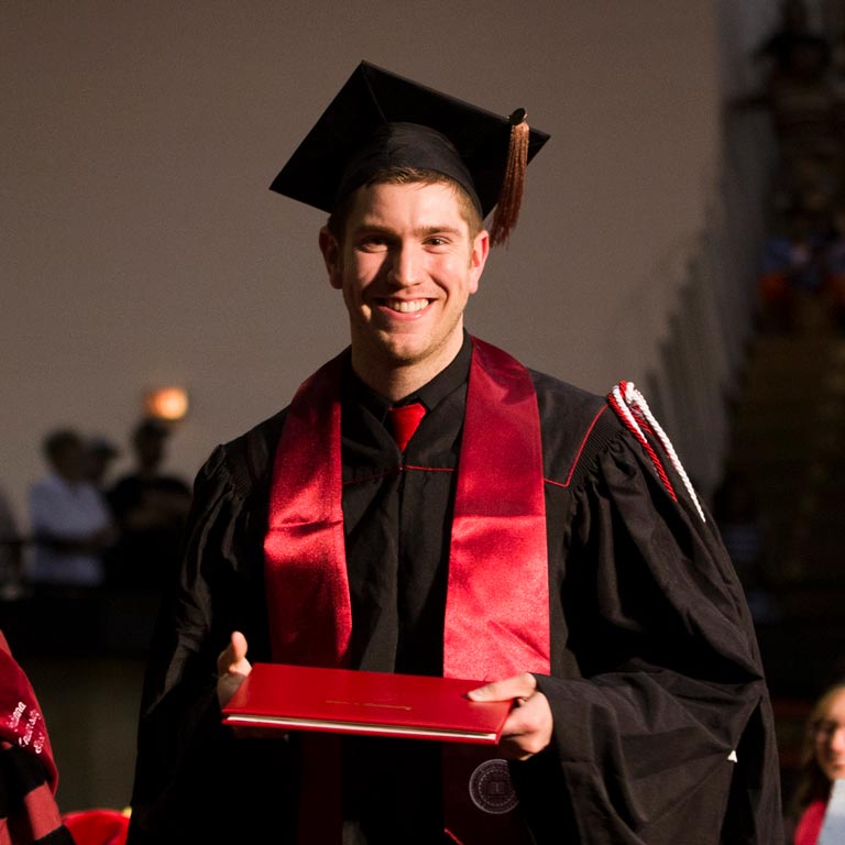 Online transfer student, Justin Westfall, smiling while receiving his diploma at Commencement.