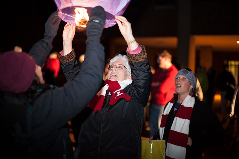 Chancellor Girten releasing a paper lantern at the homecoming bonfire.