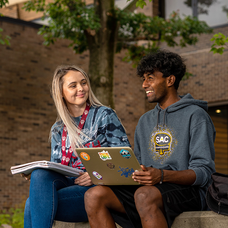 Two students sit together on the patio of Whitewater Hall.